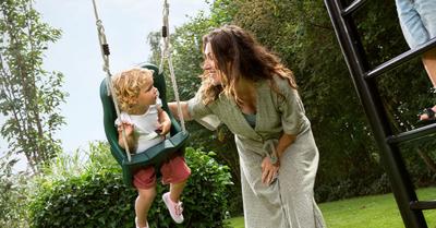 Banner med BERG PlayBase klätterställning där mamma och barn leker tryggt i trädgården