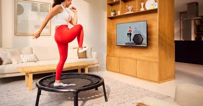 Kvinde laver fitnessøvelser på BERG mini trampolin med online træning