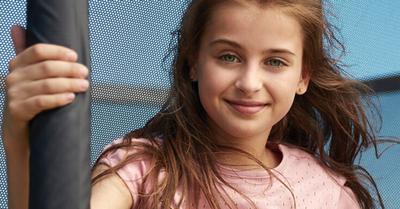 Banner with girl at a BERG trampoline with safety net on a sunny day