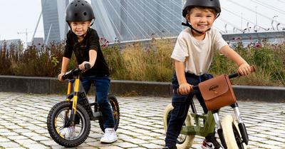 Due bambini guidano biciclette senza pedali BERG Biky su un molo con vista su un ponte