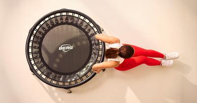 Vrouw doet fitnessoefeningen op BERG mini trampoline, bovenaanzicht – banner