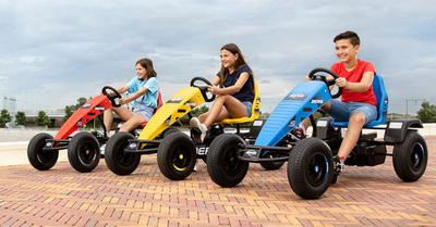 Tres niños montando karts a pedales BERG de diferentes colores en un día soleado