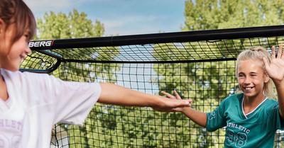 Niños juegan al balonmano cerca de una BERG SportsGoal en el jardín – banner
