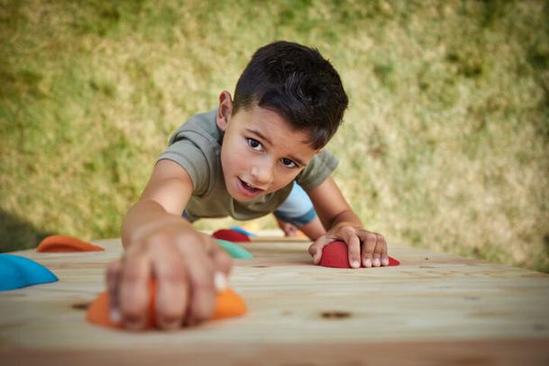 Ragazzo scala un giochi da giardino BERG PlayBase con parete da arrampicata in legno
