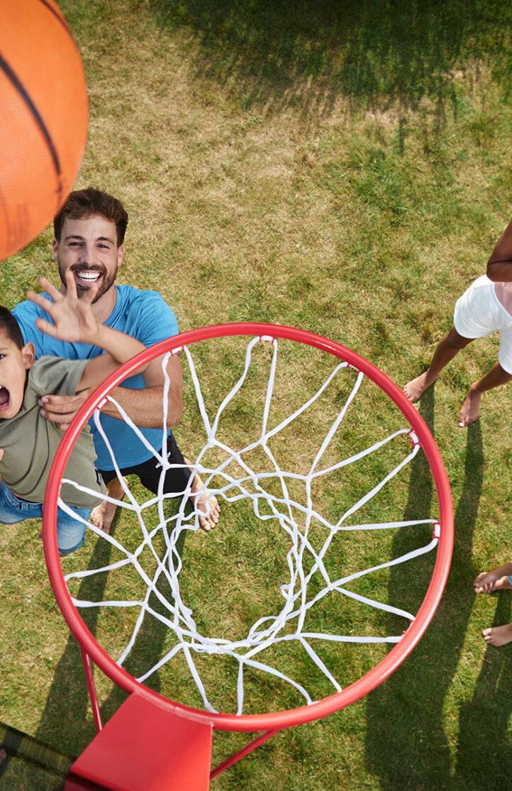 Gezin speelt basketbal op een BERG PlayBase speeltoestel in de tuin