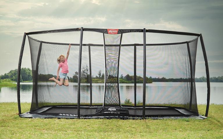 Child jumps on a BERG Ultim Elite trampoline for public use near a lake