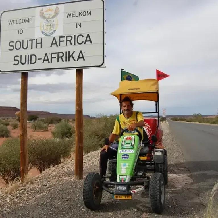 Pedal Joe with his BERG pedal kart at the South Africa welcome sign on a deserted road