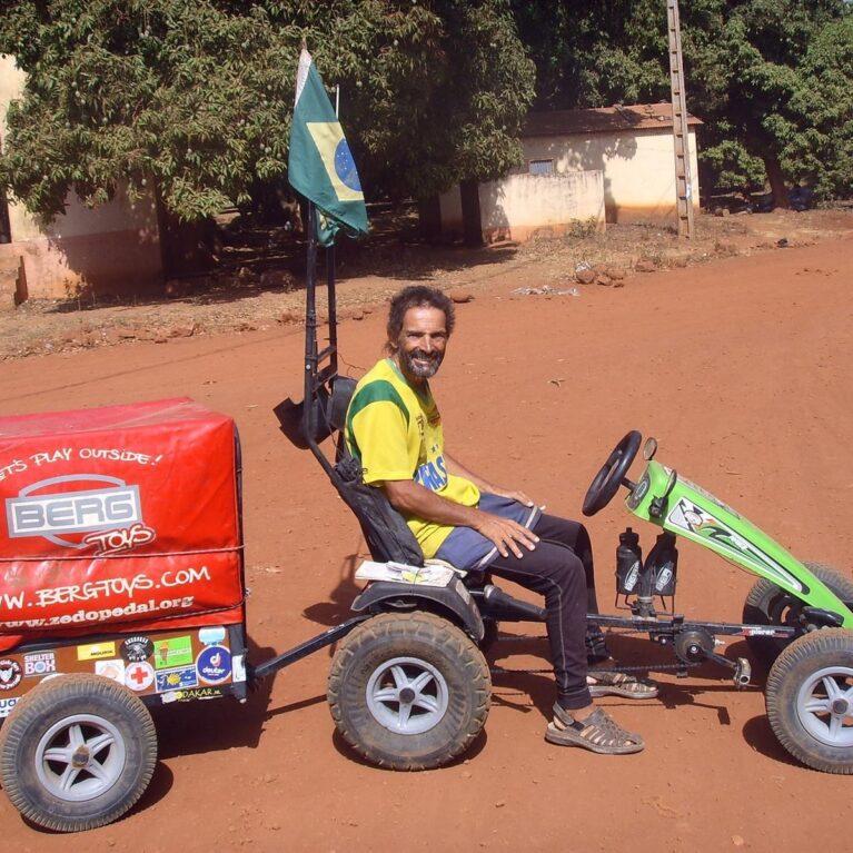 Pedal Joe with his BERG pedal kart and trailer on a red dirt road in Bamako, Mali