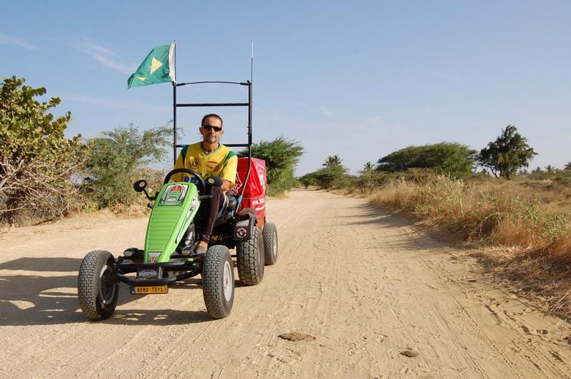 Pedal Joe kører på en BERG offroad gokart med flag og lad på en støvet grusvej