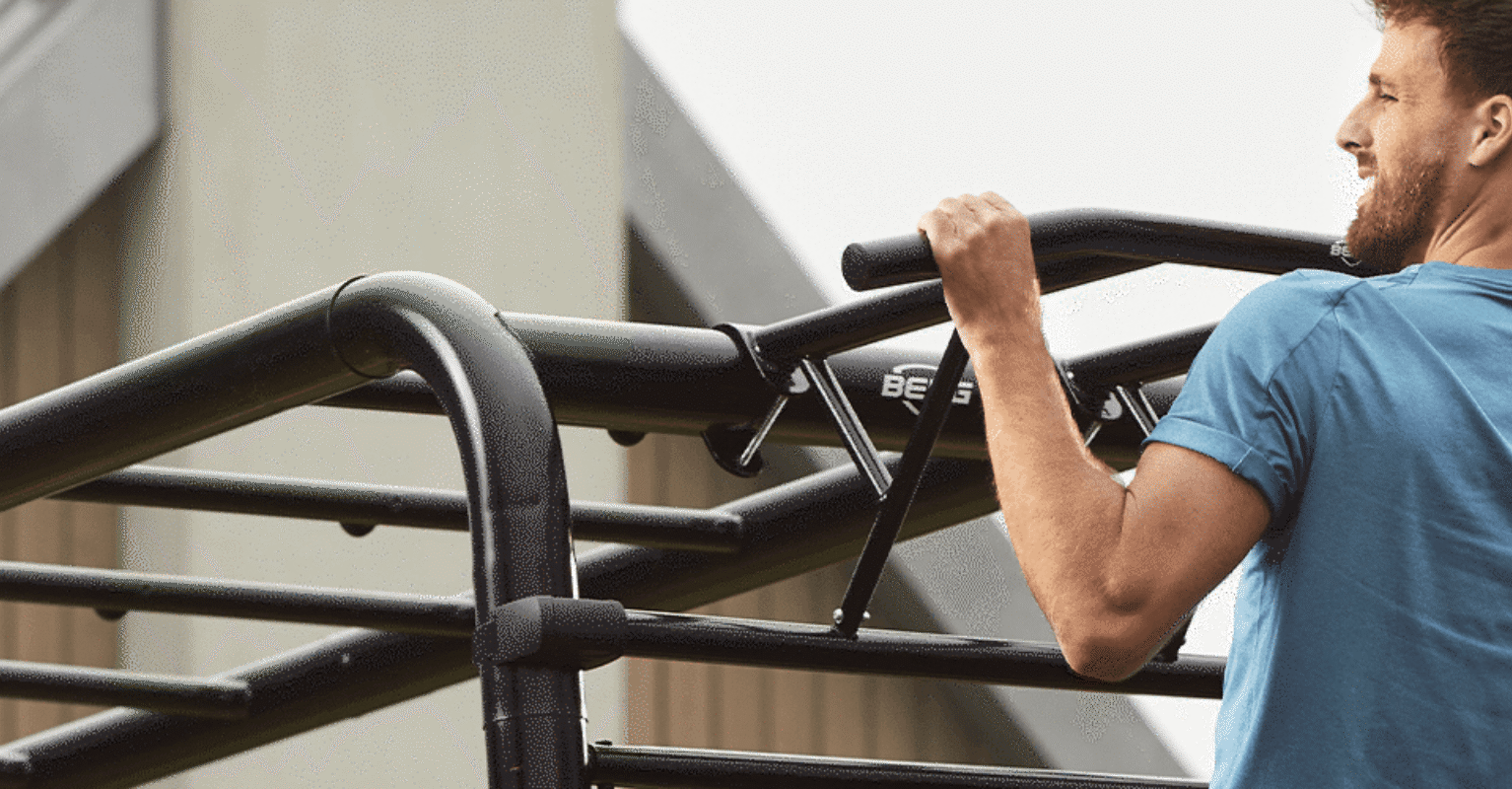 Banner mit Mann, der Klimmzüge an der BERG PlayBase als Homegym bei einem modernen Haus macht