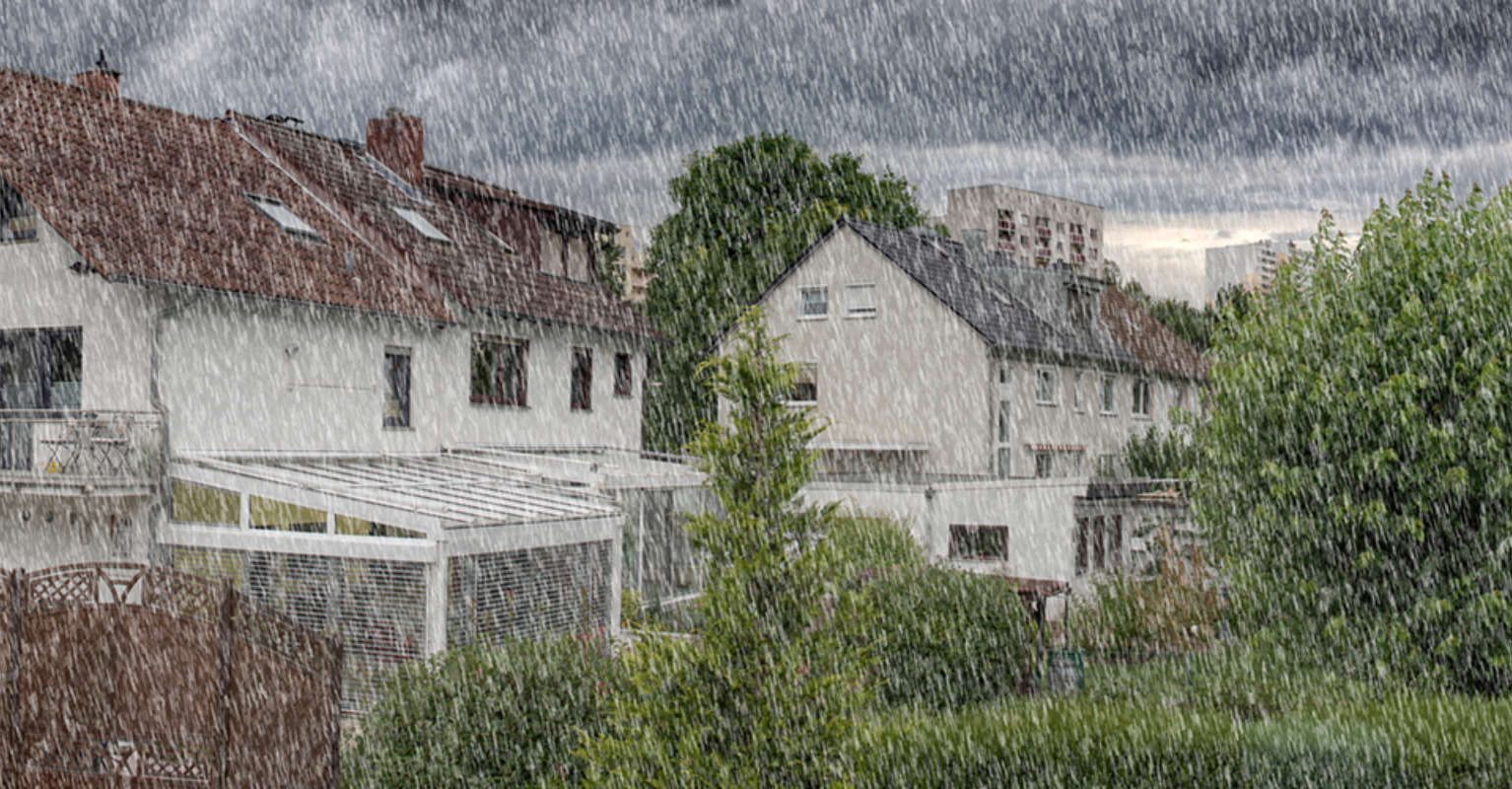 Banner van een woonwijk met huizen en bomen tijdens een zware regenbui en donkere lucht