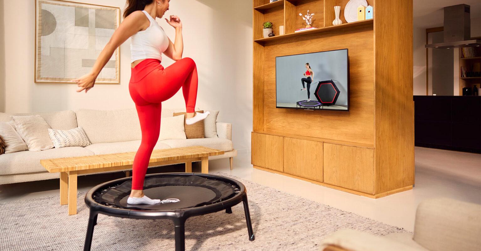 Frau macht Fitnessübungen auf BERG Mini-Trampolin mit Online-Training