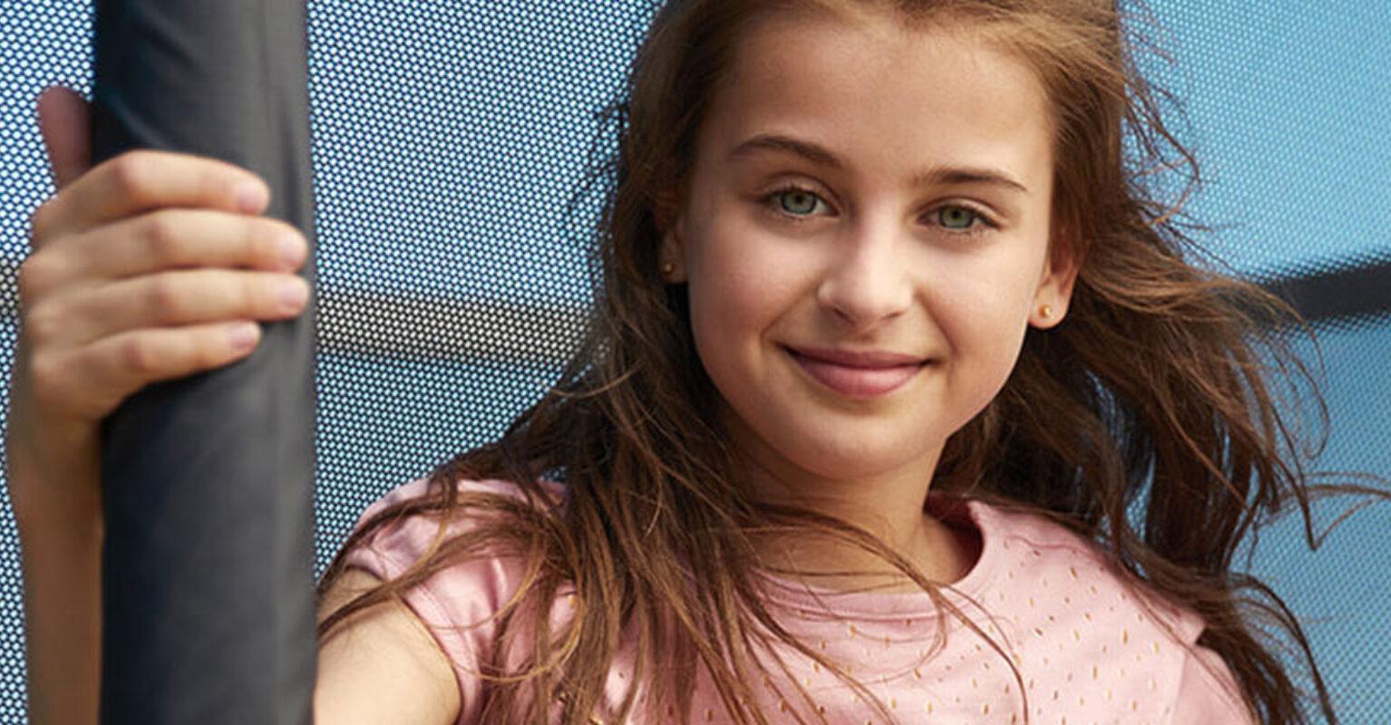 Banner mit Mädchen an einem BERG Trampolin mit Sicherheitsnetz an einem sonnigen Tag