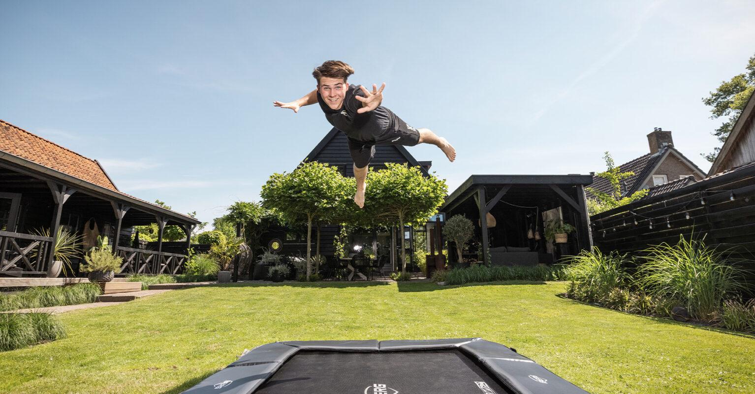 Saut spectaculaire sur un trampoline BERG dans un jardin verdoyant | Banner