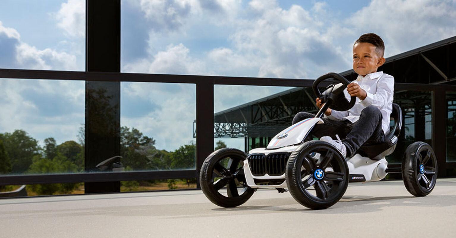 Jongen rijdt op een BERG Reppy BMW skelter op een betonnen terras